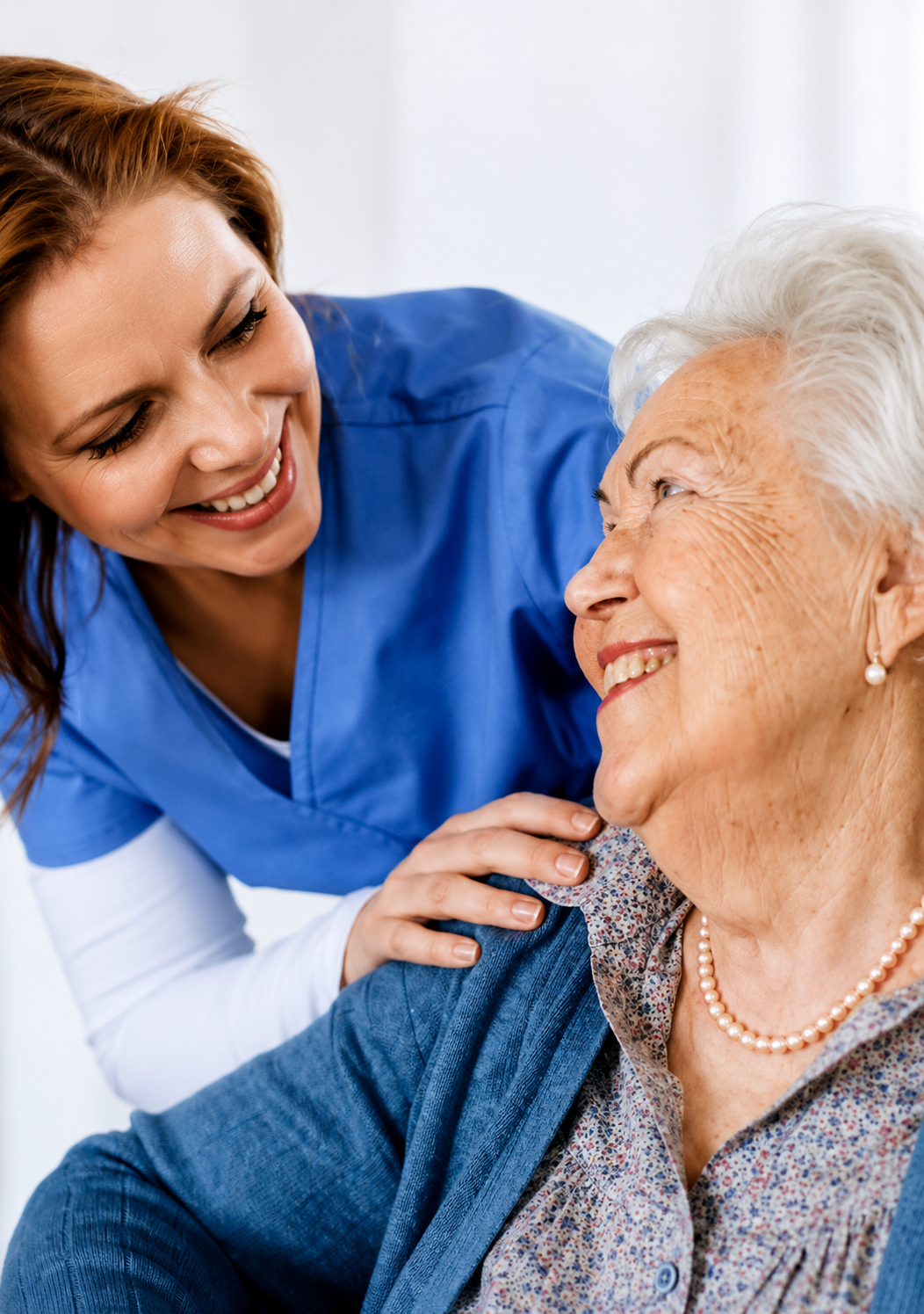 Caregiver smiling warmly with elderly woman at home